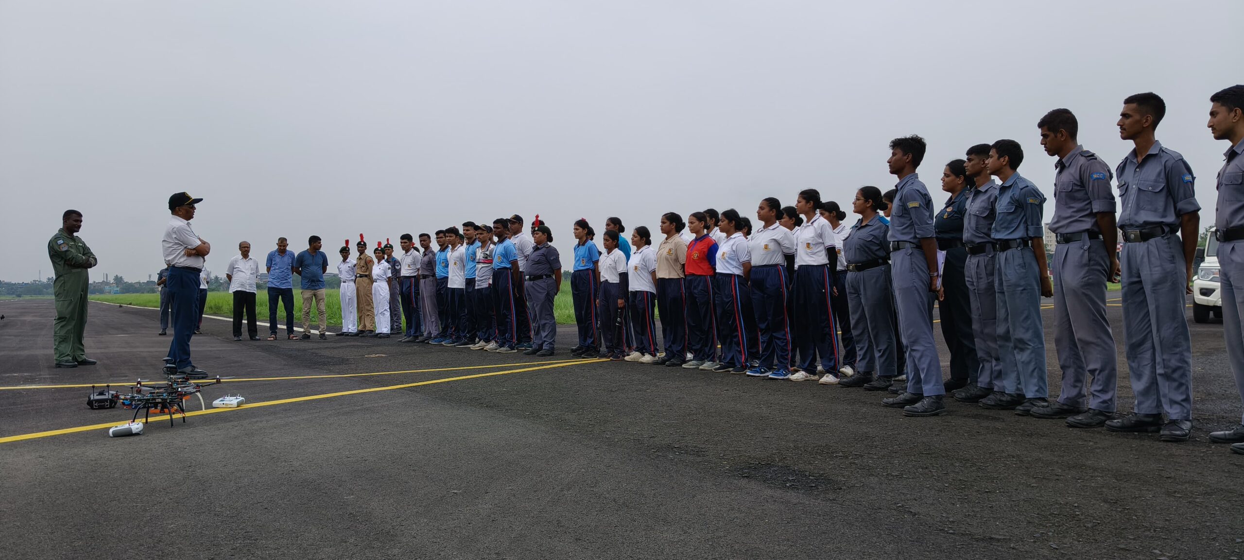 NCC Air Wing cadets in formation on the flightline at Behala Flying Club with a Weevils Drones hexacopter on the tarmac and an instructor briefing the cohort