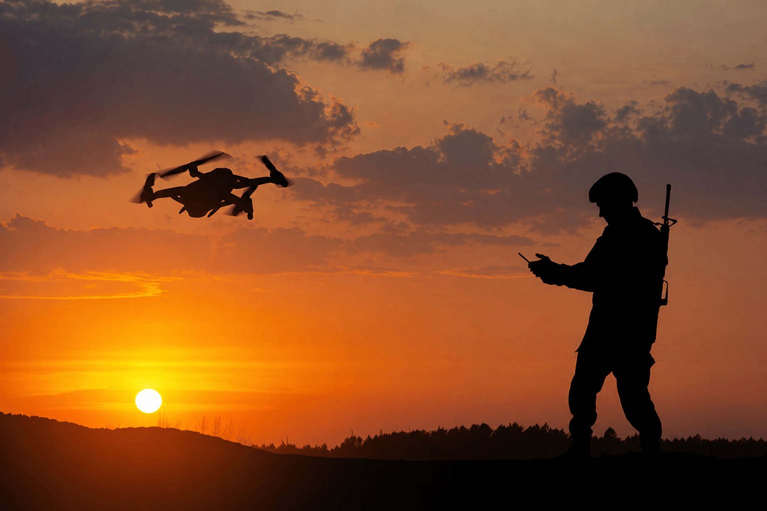 Soldier silhouette at golden hour piloting a quadcopter on a hilltop ridge, the sun setting behind a low horizon